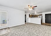 Thumbnail 61 of 74 - a living room with a ceiling fan and a kitchen in the background at Red Rock Apartments, Rapid City, SD, 57702