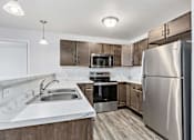 Thumbnail 14 of 74 - a kitchen with wooden cabinets and stainless steel appliances at Red Rock Apartments, Rapid City