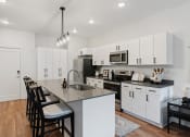 Thumbnail 67 of 84 - an open kitchen with white cabinets and a large island with black chairs