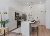 Thumbnail 94 of 126 - a kitchen with white cabinets and a long island with two chairs at SevenO2 Main Apartments, Salt Lake City, 84101