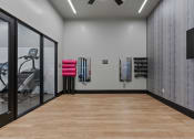 Thumbnail 77 of 126 - a fitness room with a wood floor and a wall with a tv and a treadmill at SevenO2 Main Apartments, Salt Lake City