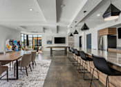 Thumbnail 29 of 136 - a large dining room with a long table and chairs and a kitchen and living room at The Flats at Riverwoods, Provo, UT, 84604
