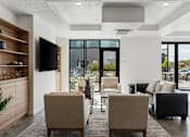 Thumbnail 62 of 136 - a living room with chairs and a table and a television at The Flats at Riverwoods, Provo