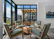 Thumbnail 59 of 136 - a living room with chairs and a coffee table and a view of a mountain at The Flats at Riverwoods, Provo