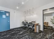 Thumbnail 31 of 136 - a conference room with a table and chairs and a blue door at The Flats at Riverwoods, Provo, 84604