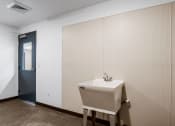 Thumbnail 71 of 136 - a sink in a bathroom with a blue door in the background at The Flats at Riverwoods, Provo, Utah