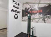 Thumbnail 73 of 136 - a room with a washing machine and a poster on the wall at The Flats at Riverwoods, Provo, Utah