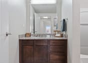 Thumbnail 23 of 71 - A bathroom with a wooden vanity and a mirror above it at Wilmington Flats Apartments, Salt Lake City, UT
