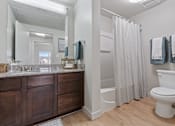 Thumbnail 24 of 71 - A white toilet sits next to a shower curtain in a bathroom. at Wilmington Flats Apartments, Utah