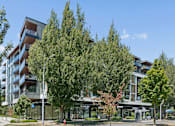 Thumbnail 22 of 28 - A modern building with a glass entrance and trees in front.
