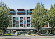 Thumbnail 24 of 28 - A modern building with a glass facade and trees in front.