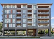 Thumbnail 26 of 28 - A modern multi-story building with balconies and large windows.