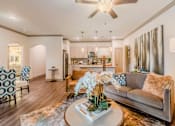 Thumbnail 20 of 27 - A living room with a grey couch and a coffee table with a vase of flowers on it at Atlas Point at Prestonwood Apartments , Texas, 75010