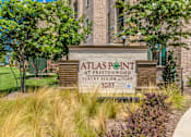 Thumbnail 11 of 27 - A sign for Atlaspoint at Prestonwood, a luxury senior living community, is displayed in front of a brick building at Atlas Point at Prestonwood Apartments , Carrollton, Texas