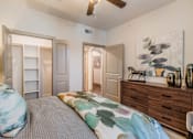 Thumbnail 26 of 27 - A bedroom with a bed, dresser, and ceiling fan at Atlas Point at Prestonwood Apartments , Carrollton, TX
