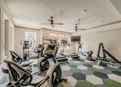 Thumbnail 6 of 27 - A spacious gym with a variety of equipment including treadmills, elliptical machines, and a rowing machine. at Atlas Point at Prestonwood Apartments , Texas