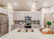 Thumbnail 16 of 27 - A modern kitchen with a granite countertop and stainless steel appliances at Atlas Point at Prestonwood Apartments , Carrollton, TX