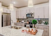 Thumbnail 14 of 27 - A kitchen with a granite countertop and a refrigerator. at Atlas Point at Prestonwood Apartments , Carrollton, TX, 75010