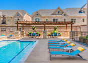 Thumbnail 4 of 27 - A pool with sun loungers and a building in the background. at Atlas Point at Prestonwood Apartments , Carrollton, 75010