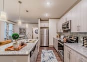 Thumbnail 17 of 27 - A kitchen with a refrigerator, oven, and sink at Atlas Point at Prestonwood Apartments , Texas