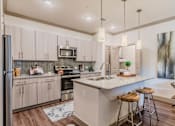 Thumbnail 15 of 27 - A kitchen with a white countertop and wooden floors. at Atlas Point at Prestonwood Apartments , Carrollton, 75010