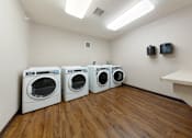 Thumbnail 9 of 28 - Three washing machines are lined up in a laundry room.