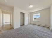 Thumbnail 8 of 28 - A spacious room with a carpeted floor and a window showing a building outside.