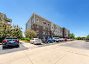 Thumbnail 16 of 28 - A parking lot with cars and apartment buildings in the background.