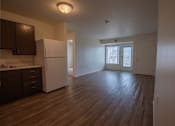 Thumbnail 12 of 21 - an empty kitchen and living room with a refrigerator and microwave