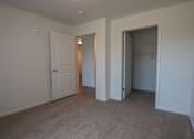 Thumbnail 14 of 21 - an empty bedroom with a closet and a door to a hallway