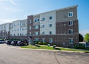 Thumbnail 1 of 11 - an apartment building with cars parked in front of it