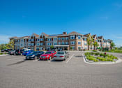 Thumbnail 8 of 8 - A parking lot with cars and a building in the background.