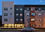 Thumbnail 1 of 12 - A modern apartment building named Thomas Avenue is shown with a car parked in front.