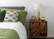 Thumbnail 14 of 52 - a bedroom with a bed with green pillows and a night stand with a lamp