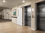 Thumbnail 50 of 52 - a hallway with two elevators and a wood floor and a door