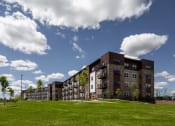 Thumbnail 29 of 52 - an apartment building on a hill with a grass field
