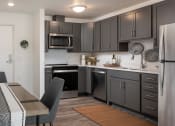 Thumbnail 45 of 52 - a kitchen with black cabinets and stainless steel appliances and a dining room table