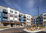 Thumbnail 12 of 19 - The image shows a multi-story residential building named Oakdale Commons with a parking lot in front.