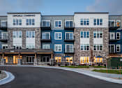 Thumbnail 14 of 19 - The image shows a multi-story residential building named Oakdale Commons with a driveway in front.