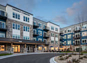 Thumbnail 15 of 19 - The image shows the exterior of Oakdale Commons apartment building at dusk.