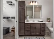 Thumbnail 5 of 19 - A bathroom with a brown cabinet and white walls.