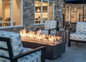 Thumbnail 10 of 19 - A patio with a fire pit and chairs.