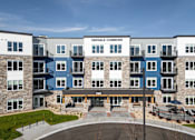Thumbnail 4 of 19 - The front of the Oakdale Commons apartment building with a blue sky in the background.