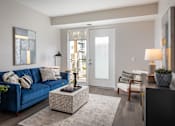 Thumbnail 2 of 20 - A living room with a blue couch and a grey rug.