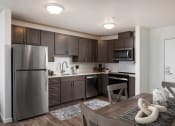 Thumbnail 10 of 25 - a kitchen and dining room with stainless steel appliances and dark wood cabinets