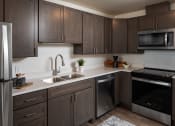 Thumbnail 2 of 25 - a kitchen with dark wood cabinets and stainless steel appliances