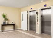 Thumbnail 16 of 25 - a lobby with two elevators and a table with a plant