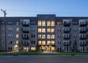 Thumbnail 4 of 25 - an apartment building with its windows lit up at dusk