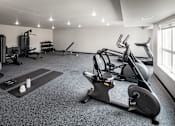 Thumbnail 6 of 11 - A spacious gym with a variety of equipment including treadmills, elliptical machines, and weights.
