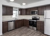 Thumbnail 2 of 11 - A kitchen with dark brown cabinets and stainless steel appliances.
